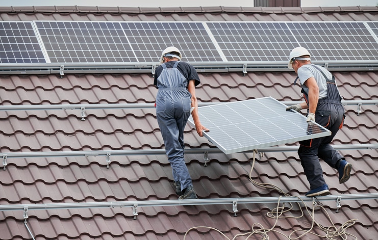 Man worker mounting solar panels on roof of house
